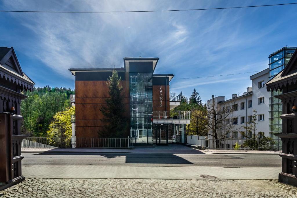 a building with a glass facade on a street at Apartamenty KAPRYS - Centrum in Krynica Zdrój