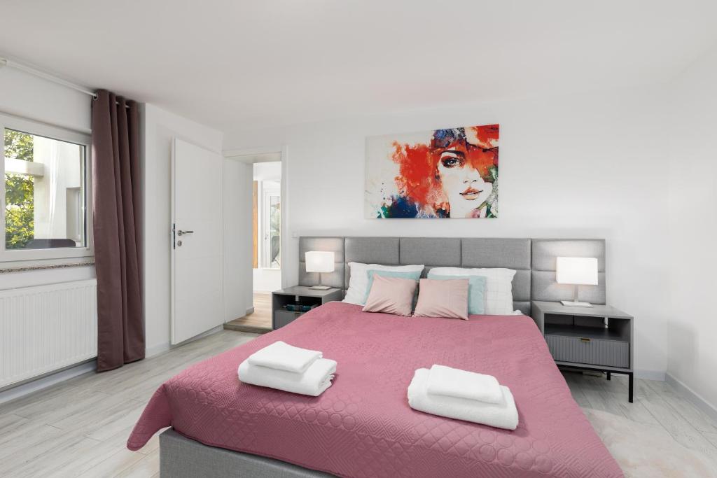 a bedroom with a large pink bed with two pillows at Apartman Grey in Slunj