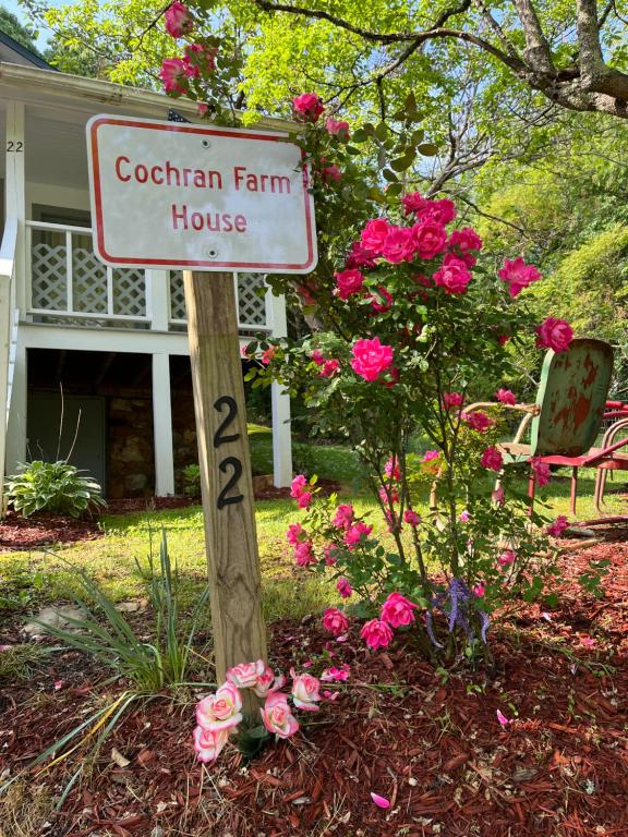 a sign in front of a house with pink roses at Cochran Farm House in Bryson City