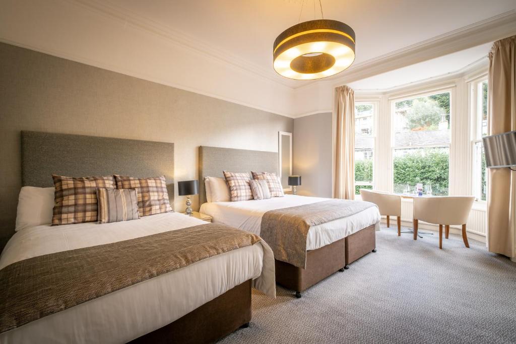 a bedroom with two beds and a large window at Ambleside Townhouse in Ambleside