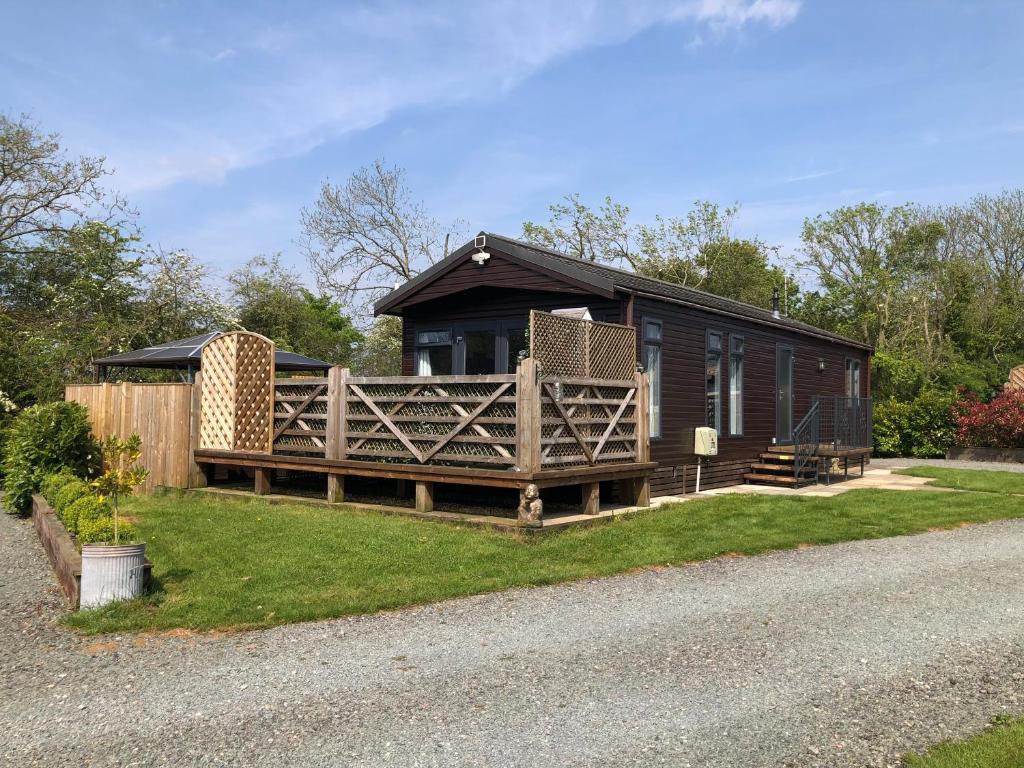 eine Hütte am Straßenrand mit einem Zaun in der Unterkunft Spacious Lodge With Hot Tub in Lincolnshire