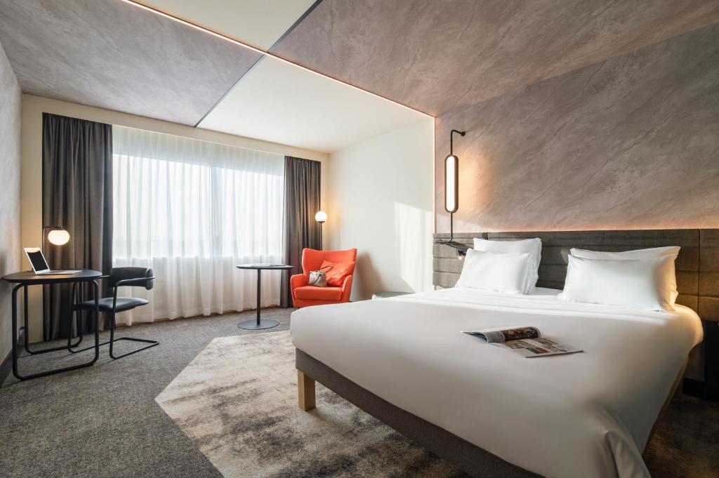 ein Hotelzimmer mit einem großen Bett und einem Stuhl in der Unterkunft Novotel Rotterdam Brainpark in Rotterdam