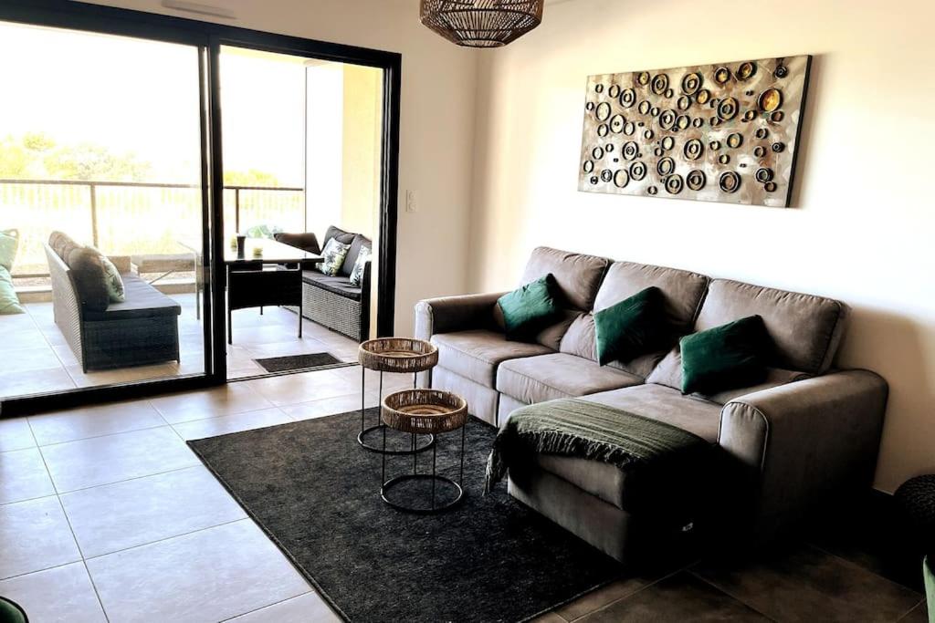 un salon avec un canapé et deux tables dans l'établissement Appartement avec terrasse 3 pièces - Vue mer - Plage 5 min à pied, à Propriano