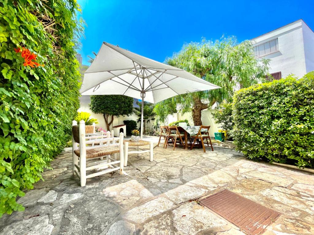 un patio con ombrellone, sedie e un tavolo di Villa vista mare con giardino e parcheggio a Nardò