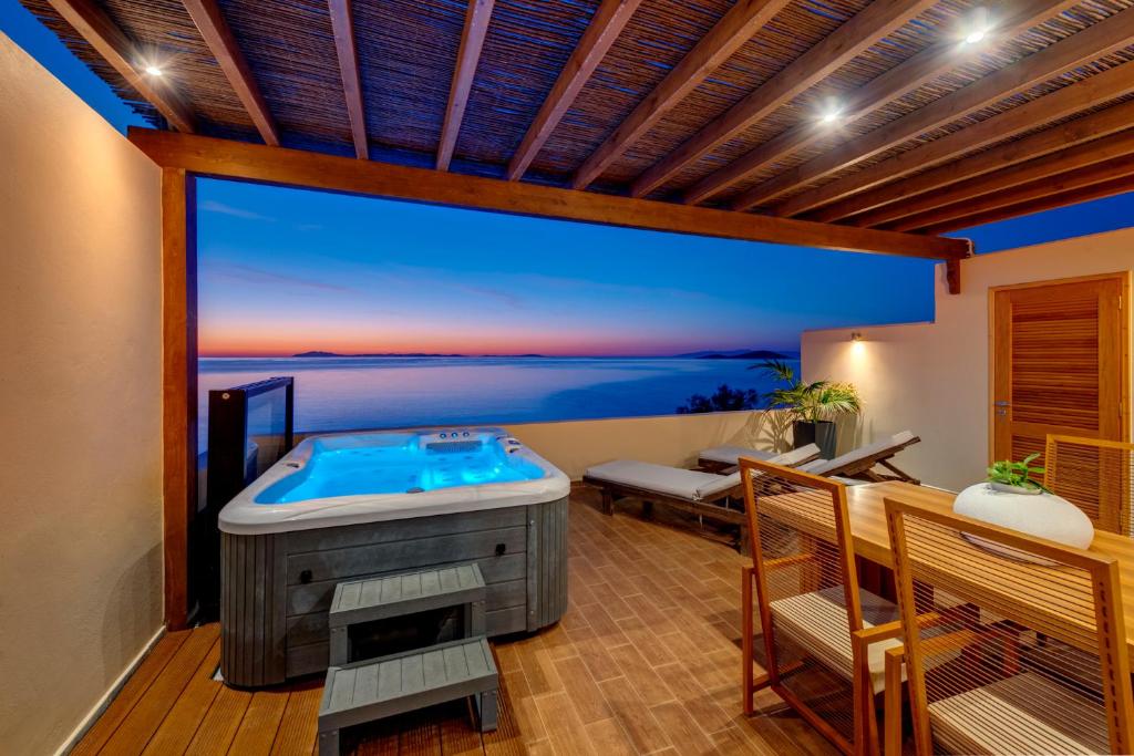 a hot tub in a room with a view of the ocean at Lalari Beach Suites in Vari