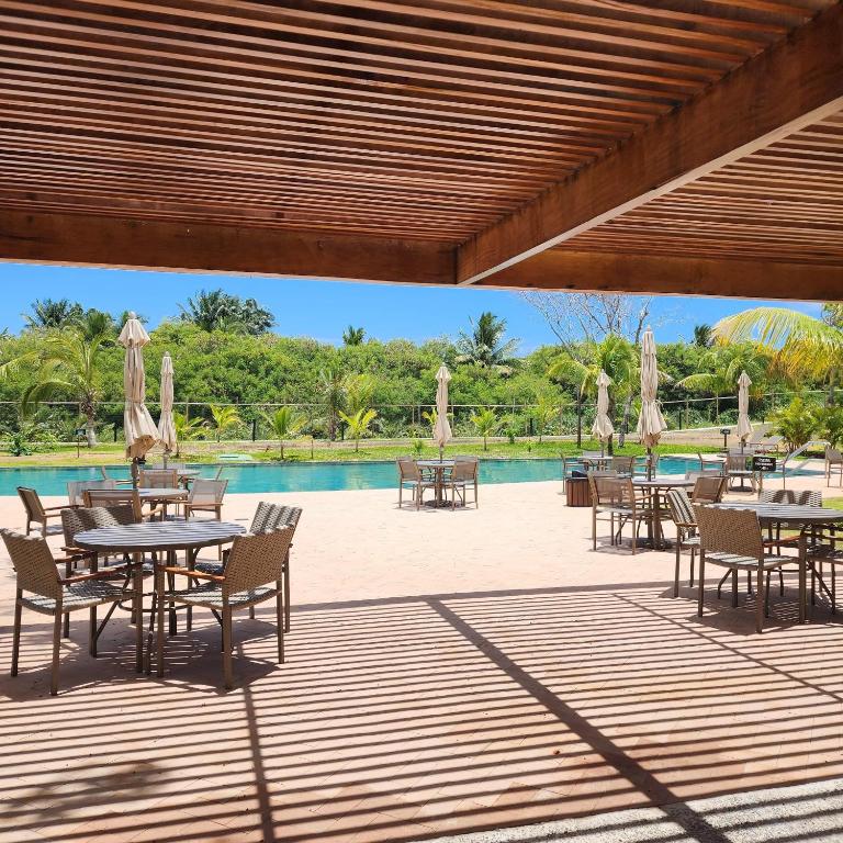 a patio with tables and chairs next to a pool at Mykonos Praia do Forte in Praia do Forte