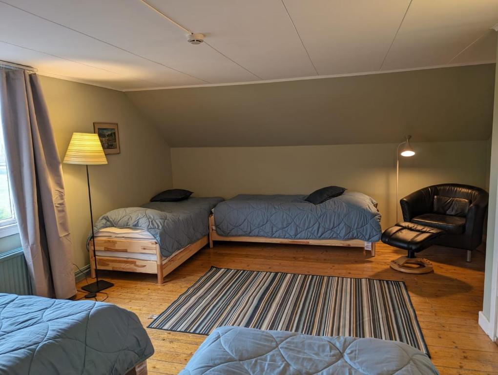 a bedroom with two beds and a chair and a lamp at Brukshotellet Öland - kursgård och vandrarhem in Degerhamn