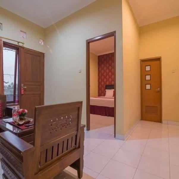 a room with a bench and a bedroom with a bed at Hotel Omah Cepit in Cepit