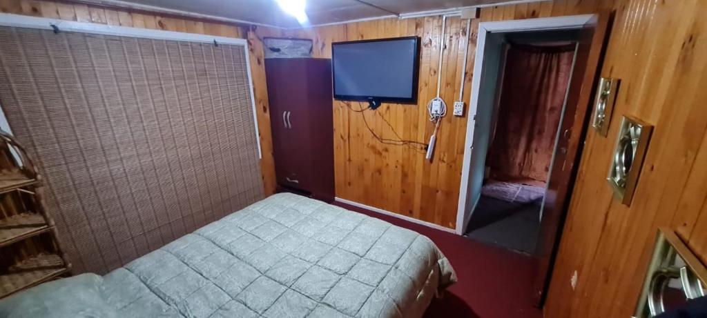 Dormitorio pequeño con cama y TV en QUELKUN, FAMILIAR, en Quellón