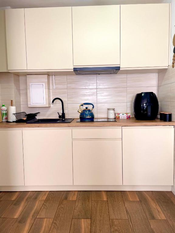 kuchnia z białymi szafkami i drewnianą podłogą w obiekcie Apartament Centrum w Łańcucie