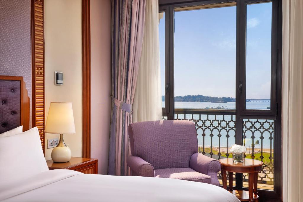 a bedroom with a bed and a chair and a window at The Ritz-Carlton Jeddah in Jeddah