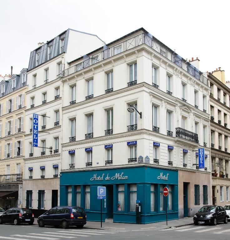 un grand bâtiment blanc avec des voitures garées devant dans l'établissement Hotel de Milan, à Paris