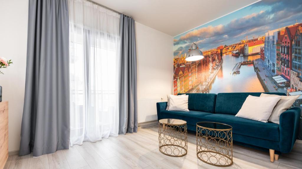 a living room with a blue couch and a painting at City Center SPA Apartments Pool & Parking in Gdańsk