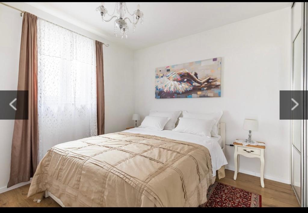 a white bedroom with a bed and a chandelier at Apartments Petra in Split