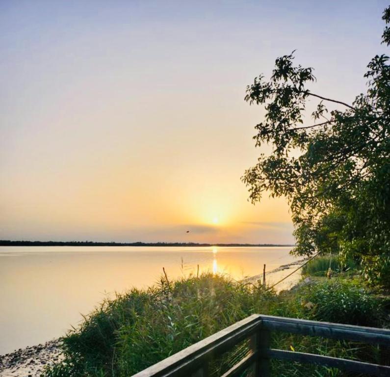 un coucher de soleil sur une étendue d'eau avec une clôture dans l'établissement Gîte au bord de la Gironde, à La Reuille