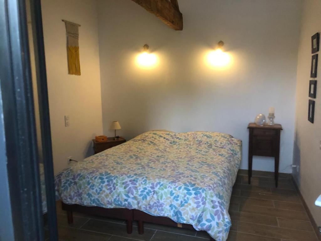 1 dormitorio con 1 cama y 2 luces en la pared en La Grange de la Brousse en La Brousse