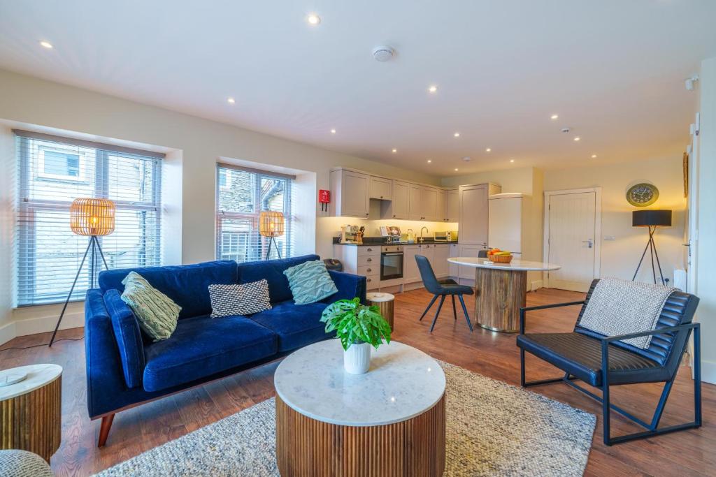 a living room with a blue couch and a kitchen at Weavers Two - Luxury Apartment for Two in Windermere