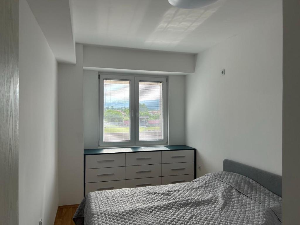 um quarto com uma cama e uma janela em GJP em Skopje