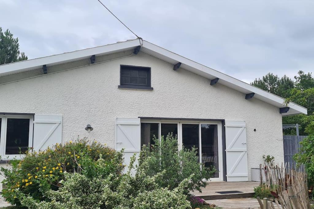 ein weißes Haus mit einem Fenster und einigen Büschen in der Unterkunft Villa indépendante avec piscine in Arès