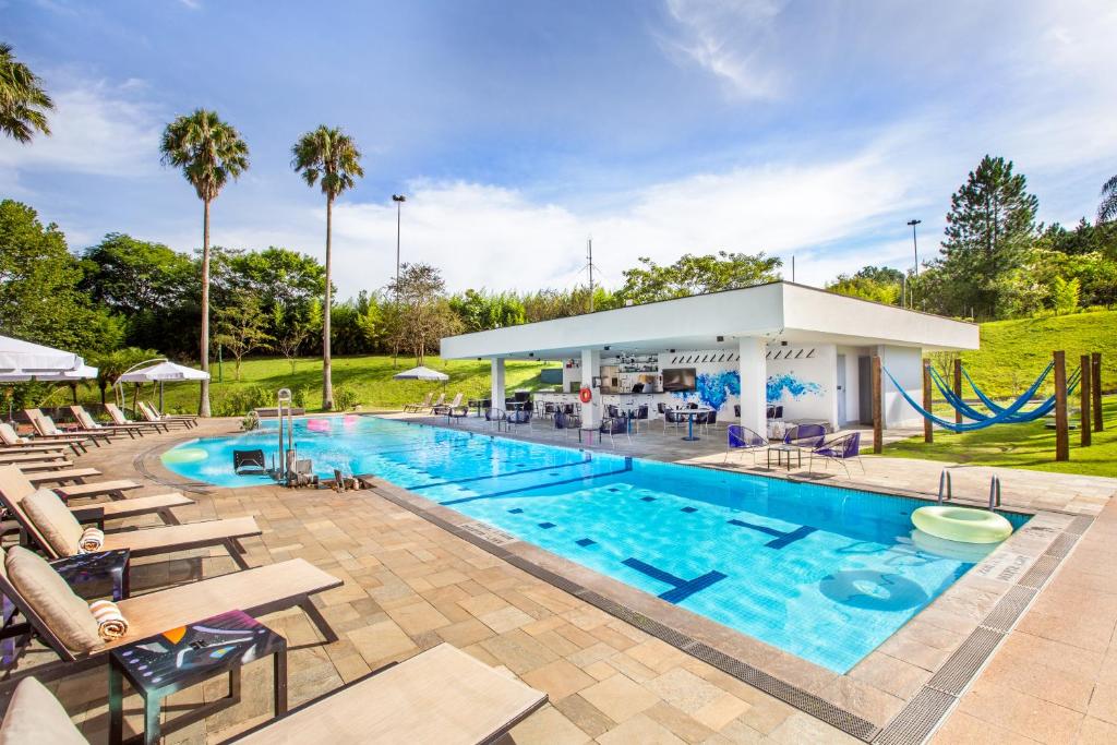 einen großen Pool mit Stühlen und Rutsche in der Unterkunft Pullman Sao Paulo Guarulhos Airport in Guarulhos