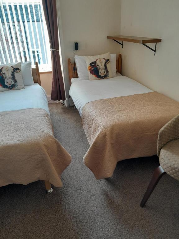 a room with two beds and a chair and a window at parkhill guest house in Inverness
