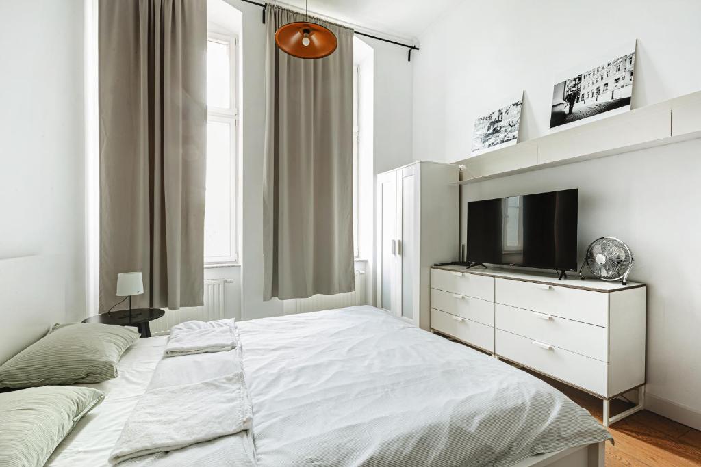 a white bedroom with a bed and a tv at Komfortowy apartament w samym centrum Wrocławia in Wrocław
