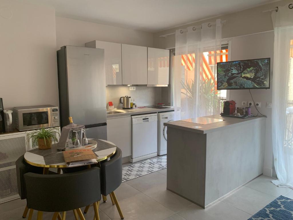 une cuisine avec des armoires blanches et une table et des chaises dans l'établissement Idéalement situé studio éco-responsable classé 3*, à Roquebrune-Cap-Martin