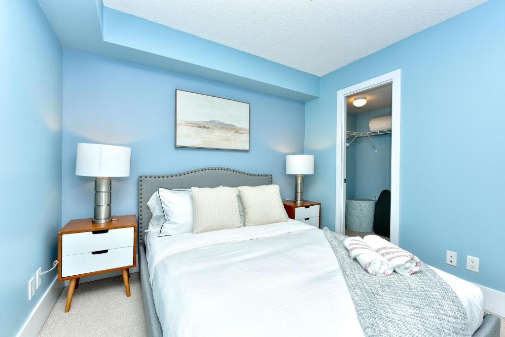 a blue bedroom with a bed and a mirror at 300 Front Suites in Toronto