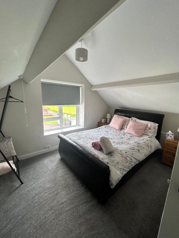 Un dormitorio con una cama con almohadas rosas y una ventana en Eddies Lodge & Spa 3 bedroom cottage, en Dungiven
