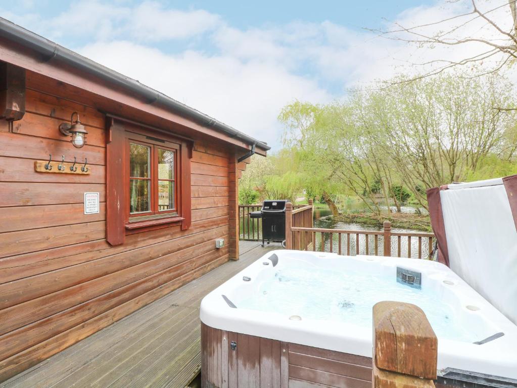 bañera de hidromasaje en la cubierta de una cabaña en Kingfisher Lodge 