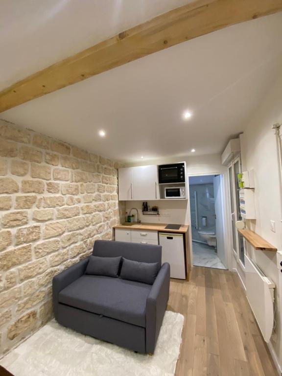 un salon avec un canapé et un mur en pierre dans l'établissement Appartement neuf à louer, Paris Sacré Cœur, à Paris