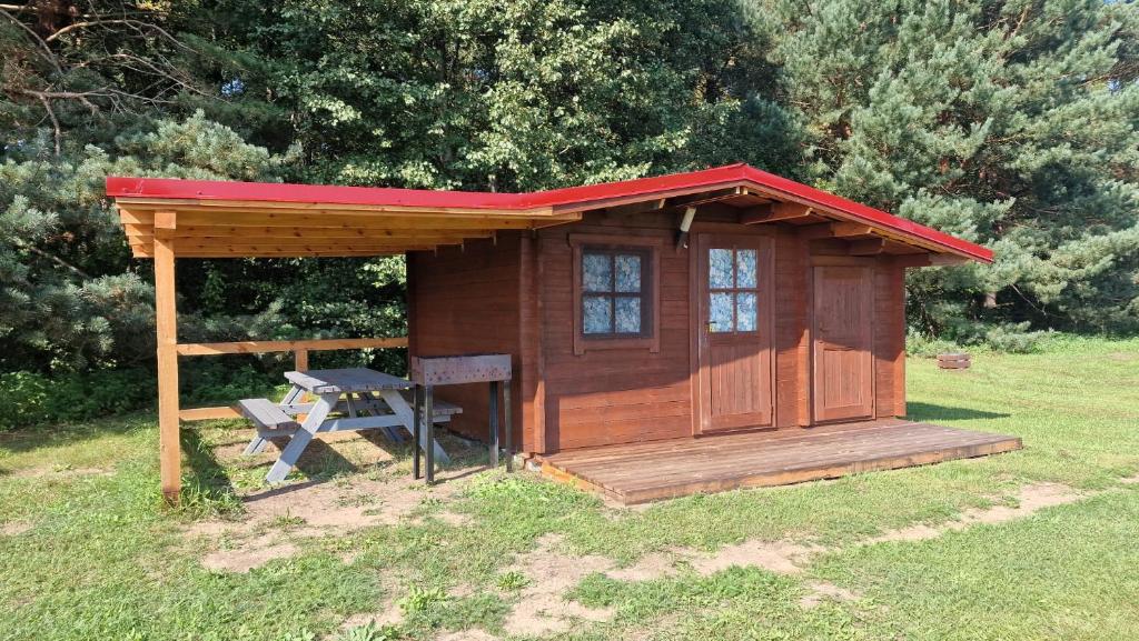 a wooden cabin with a bench in the grass at SP camping Spāres Prieduļi in Nīca