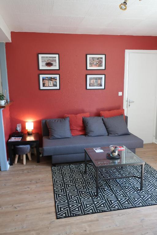 - un salon avec un canapé et un mur rouge dans l'établissement Appartement avec jardin au coeur de Rennes, à Rennes