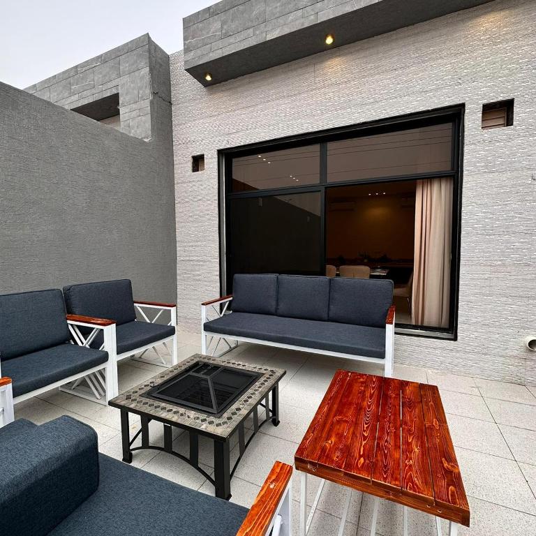 un patio con sofás azules y una mesa de centro en منتجعات رغيد الفندقية, en Hail