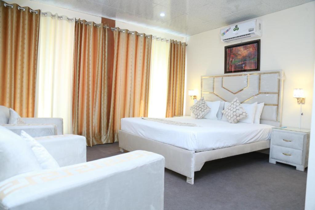 a hotel room with two beds and two chairs at Hotel palm east lahore in Lahore