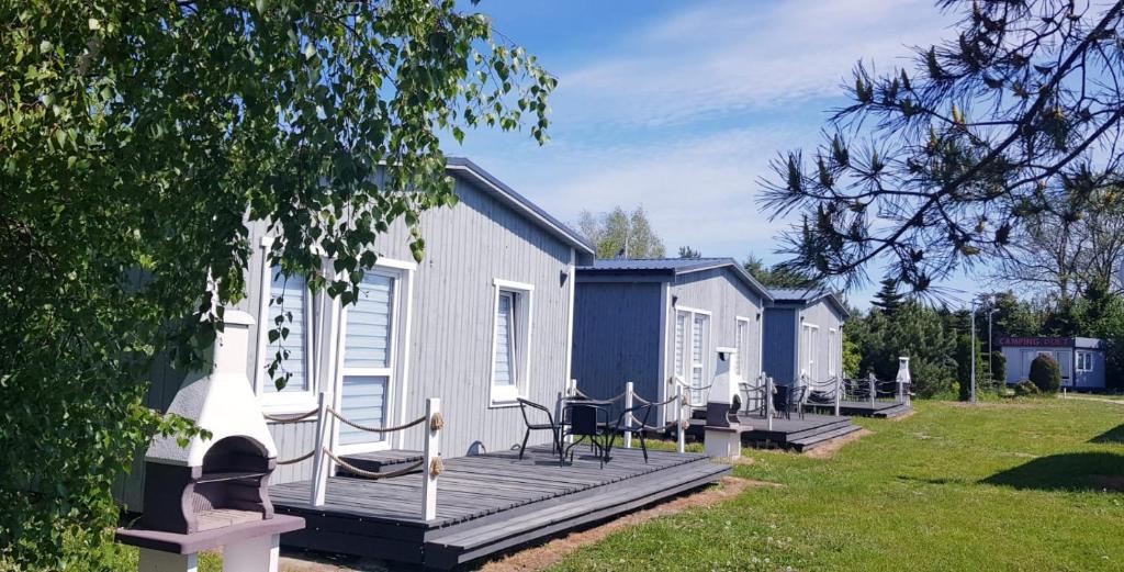 een huis met een terras met stoelen en een tafel bij Kompleks Wypoczynkowy DUET in Niechorze