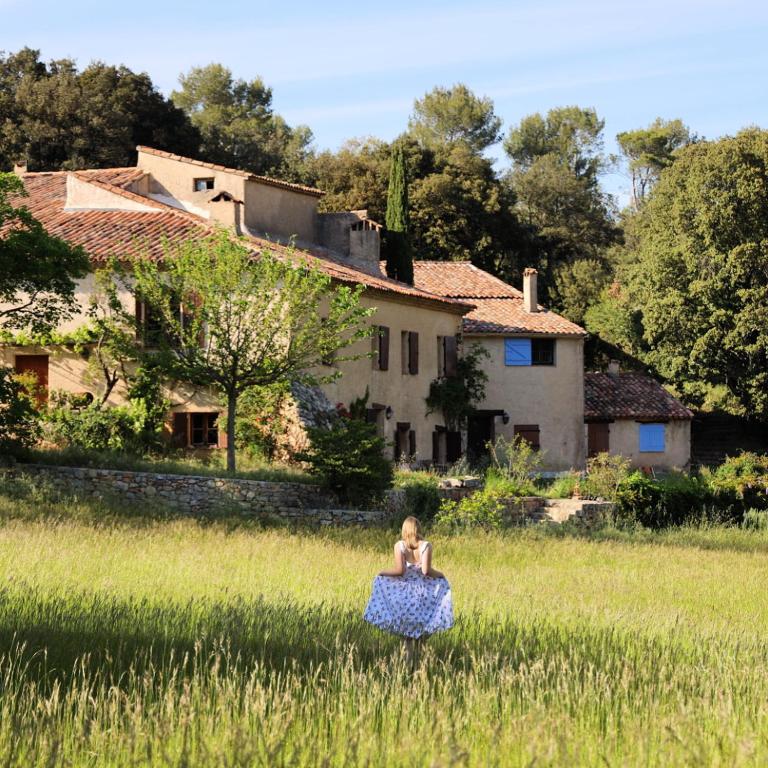 une fille assise dans un champ devant une maison dans l'établissement Domaine Les Vaches, à Cotignac