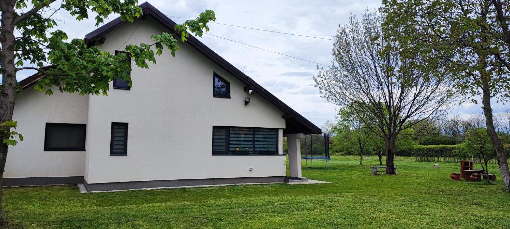 a white house with black windows and a yard at La Coti in Braşov