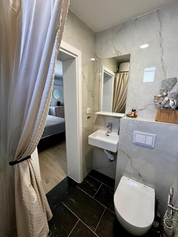 a bathroom with a white toilet and a sink at Sha Sho in Mostar