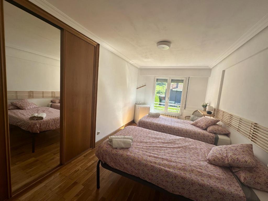 a bedroom with two beds and a mirror at Habitaciones Hondar-Gain 10 in Zumaia