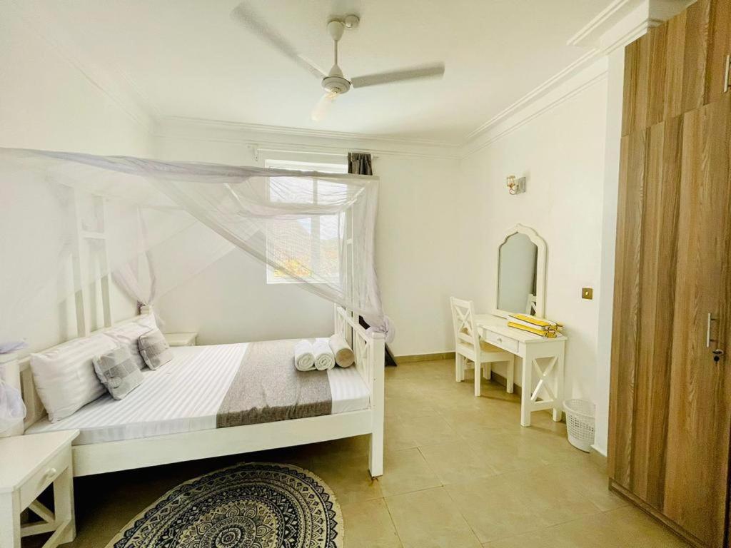 a bedroom with a bed and a table and a mirror at Ammerville Diani in Diani Beach