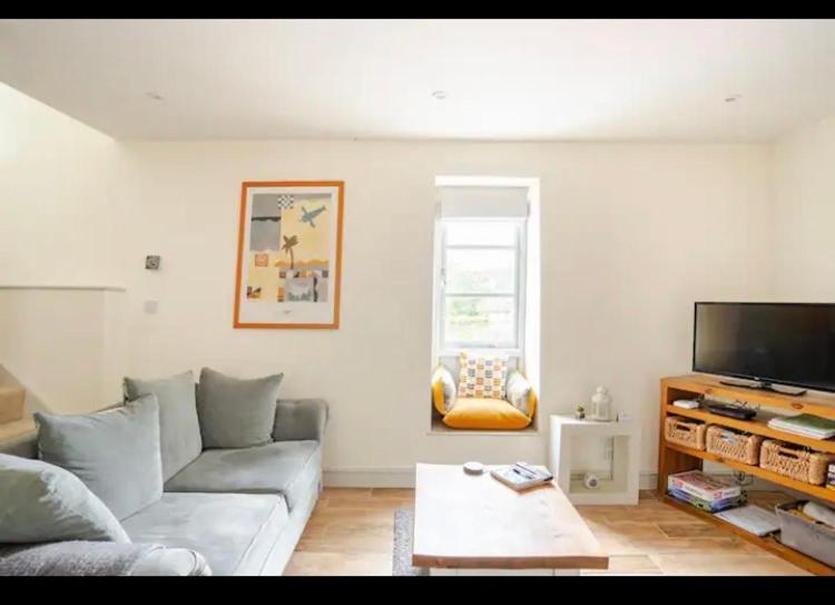 a living room with a couch and a tv at Stans Place Self Catering Cottage in Malmesbury