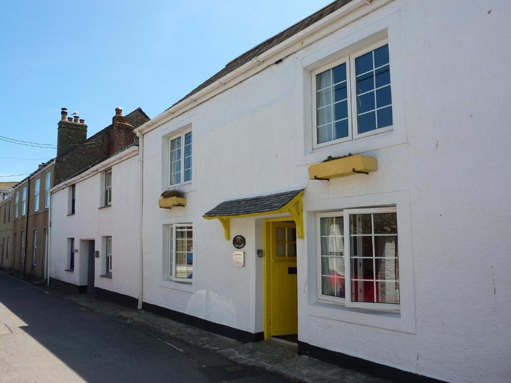 a white building with a yellow door on a street at April Cottage in Coverack