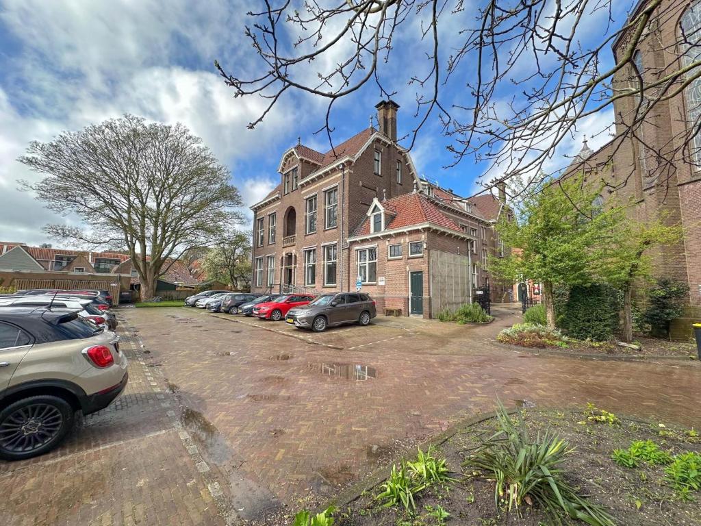 a large brick building with cars parked in a parking lot at Grote Weeshuis in Enkhuizen