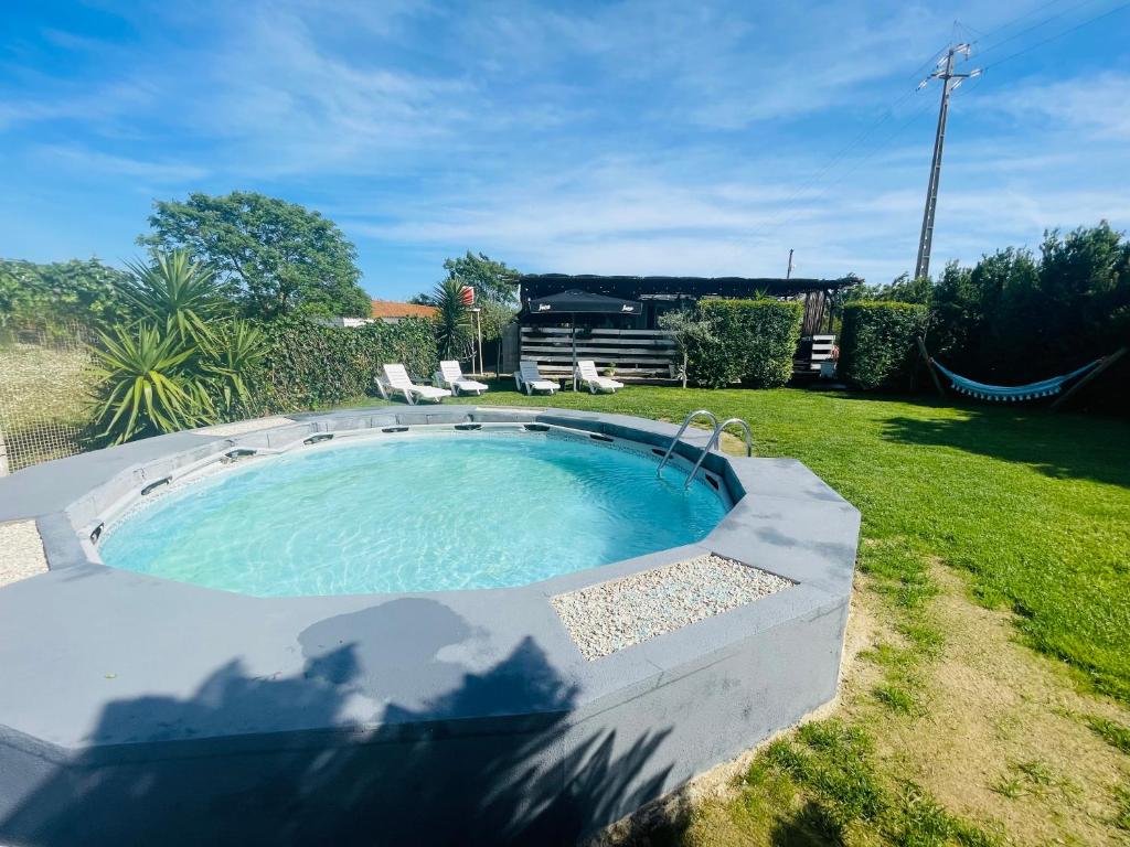 einen Pool in einem Garten mit Stühlen im Gras in der Unterkunft Monte do Bidé Private Farm Peace and Nature in Setúbal