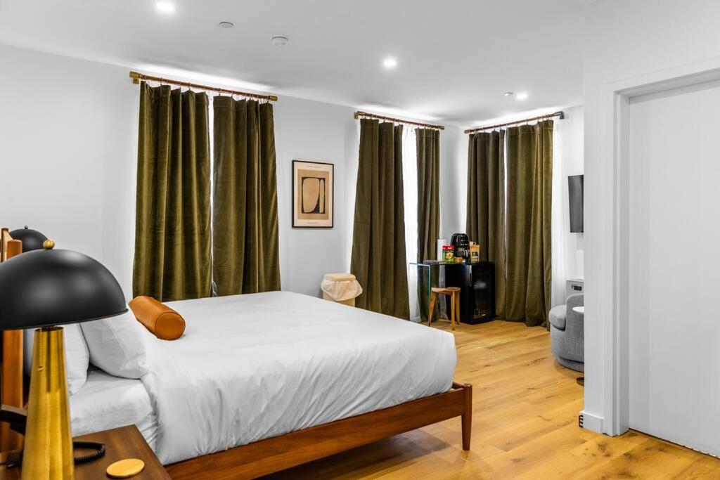 1 dormitorio con cama blanca y cortinas verdes en King Bed, DTWN Historic Hotel, Fiber Wifi, 50 in Roku TV, Room # 106, en Bangor