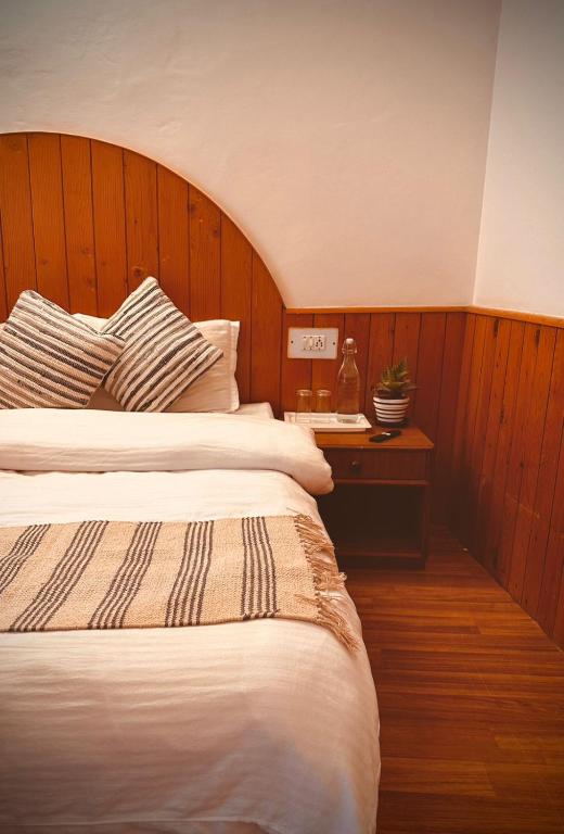 a bedroom with a bed with a wooden headboard at Drifters Inn - The Hidden Tribe in Manāli