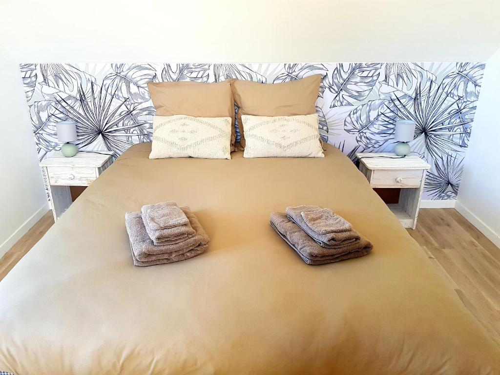 - une chambre avec un grand lit et des serviettes dans l'établissement Le Palmier des Rochers, à Saint-Léonard