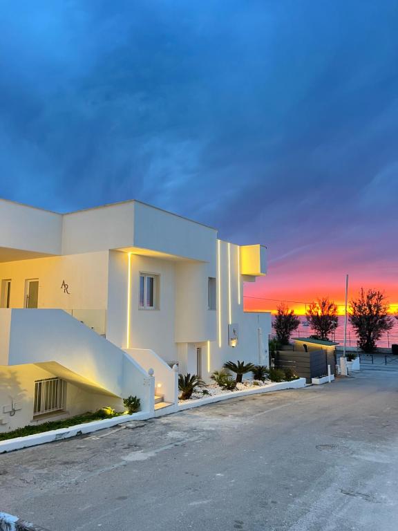 a large white building with a sunset in the background at AR Palace Hotel - Palermo in Isola delle Femmine