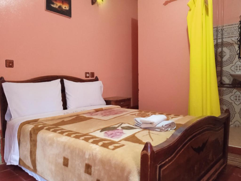 a bedroom with a large bed with a yellow curtain at Auberge Camping Garde of Eden LE LAC in Tinerhir